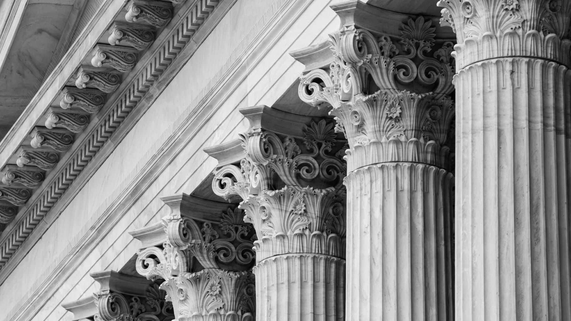 Classical marble Corinthian columns and cornice of a government building, monochrome