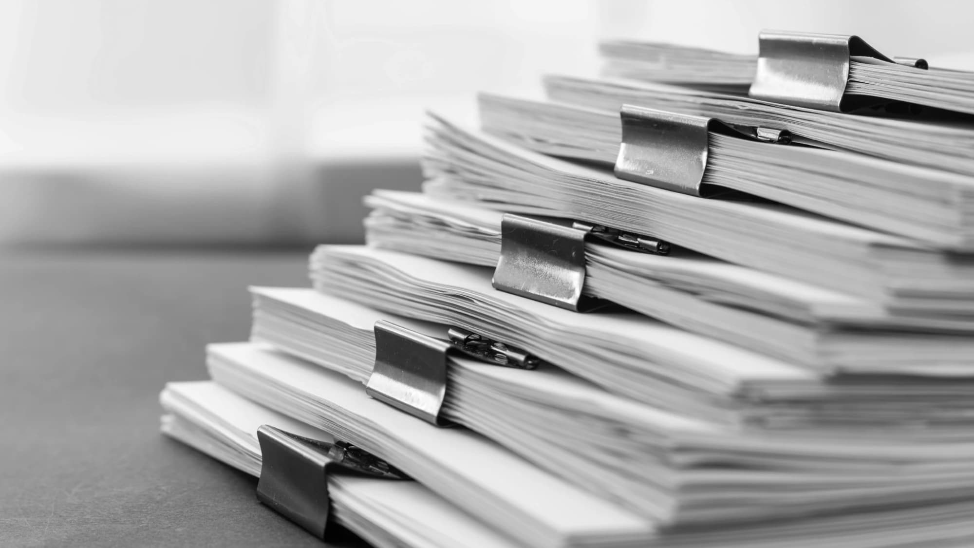 Stacks of clipped utility documents, monochrome